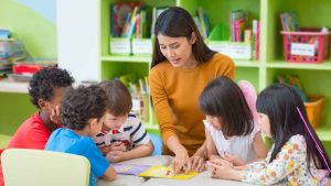 preschool teacher surrounded by students at table