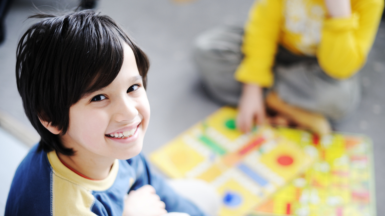 Boys playing a game with one smiling