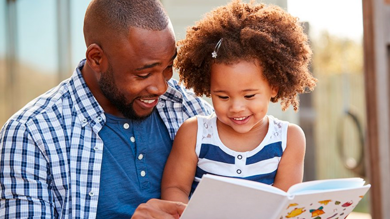 Dad reading to little girl in his lap