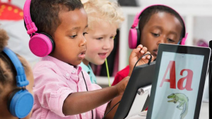 Preschool children with headphones using tablets.