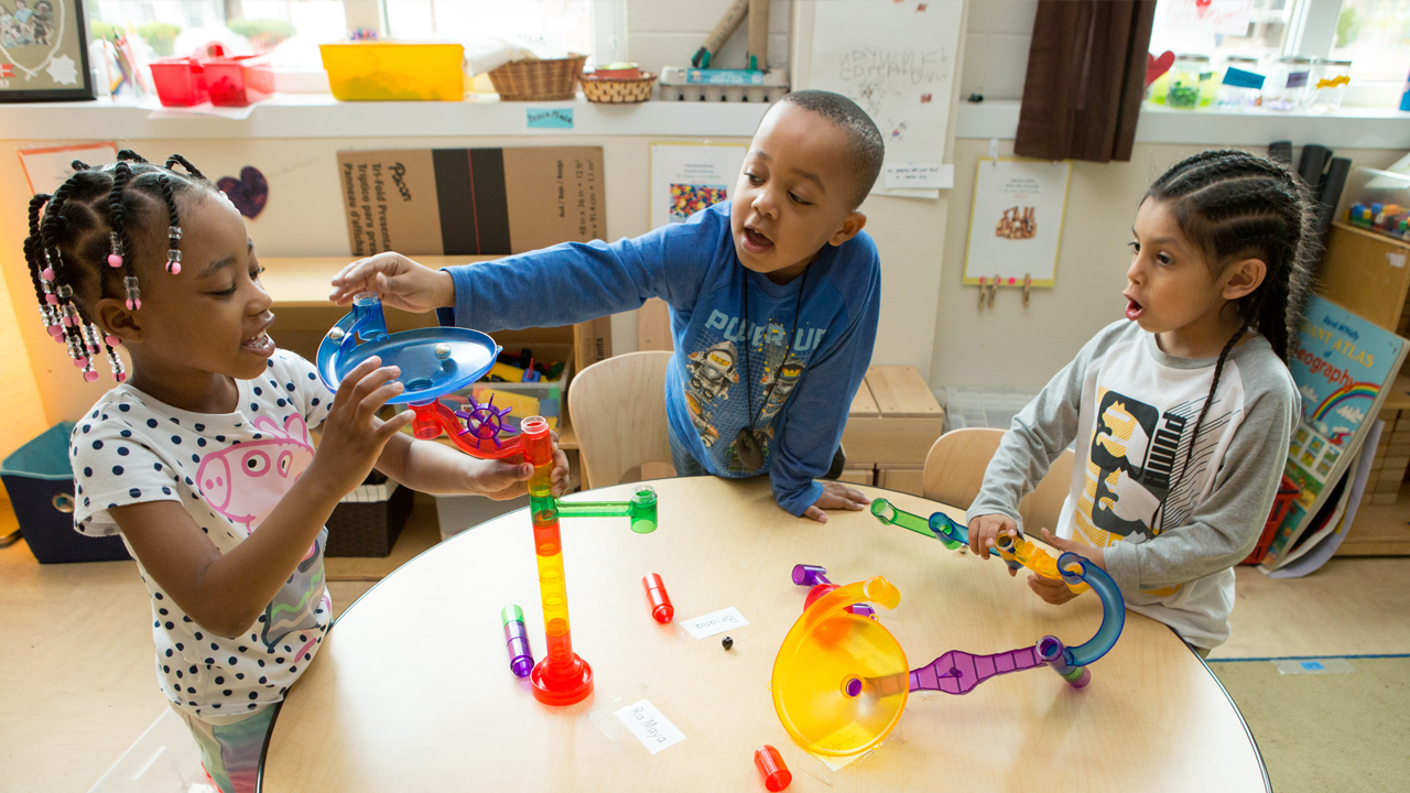 three children play with a marble run